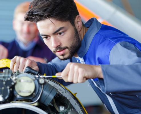 Worker Checking Airplane Engine In Airport Hangar